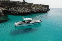 2021 Nimbus T11 T Top boat in clear turquoise water near rocky cliffs.