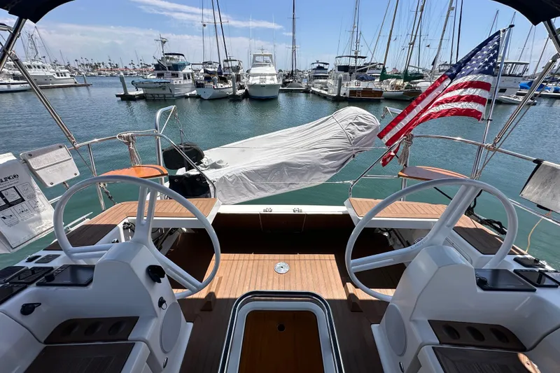 In Stock Now Yacht Photos Pics Cockpit view of 2018 Elan 45 Impressions yacht in marina, featuring dual steering wheels.