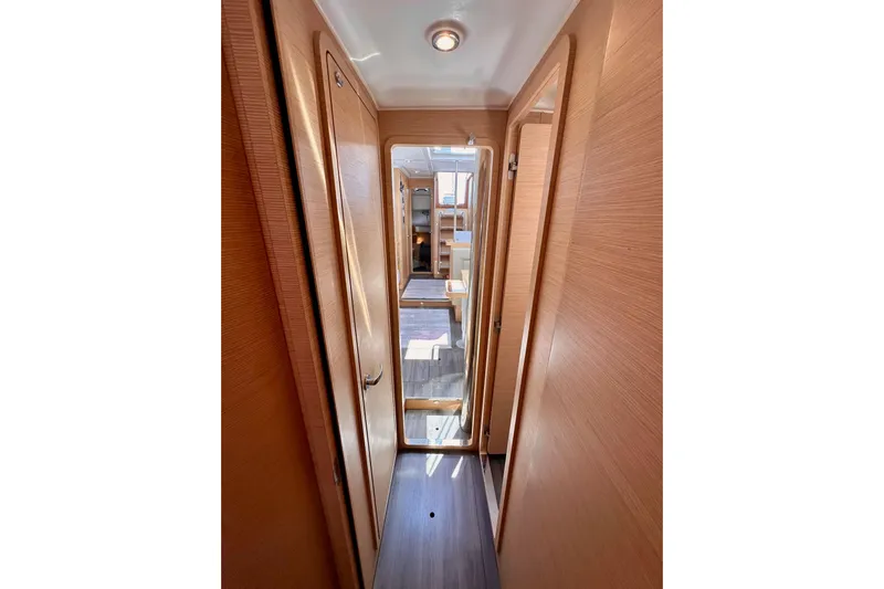 In Stock Now Yacht Photos Pics Narrow hallway inside 2018 Elan 45 Impressions yacht, featuring wooden doors and flooring.