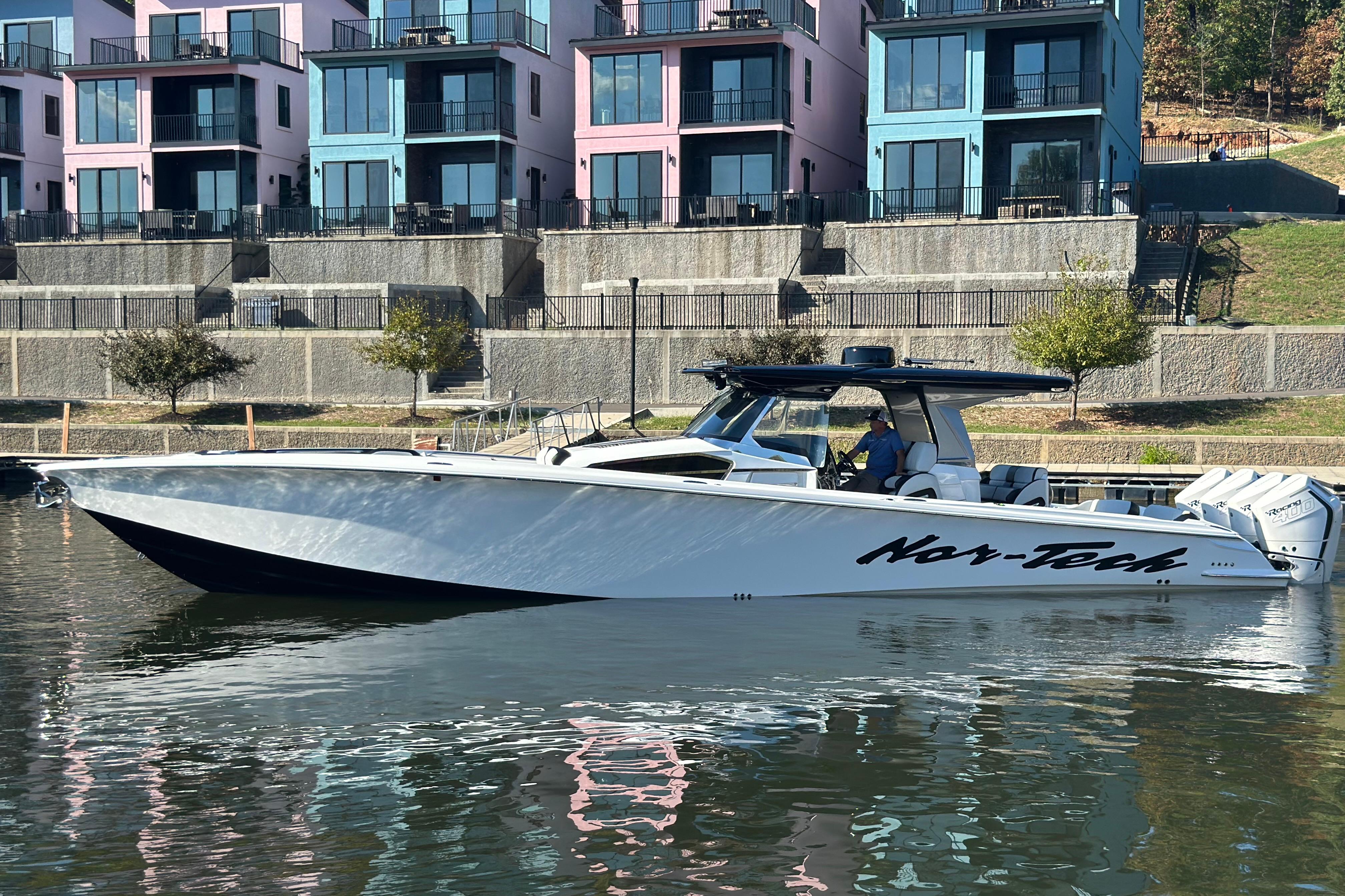 2025 Nor-Tech 450 Sport Center Console boat docked near colorful buildings.