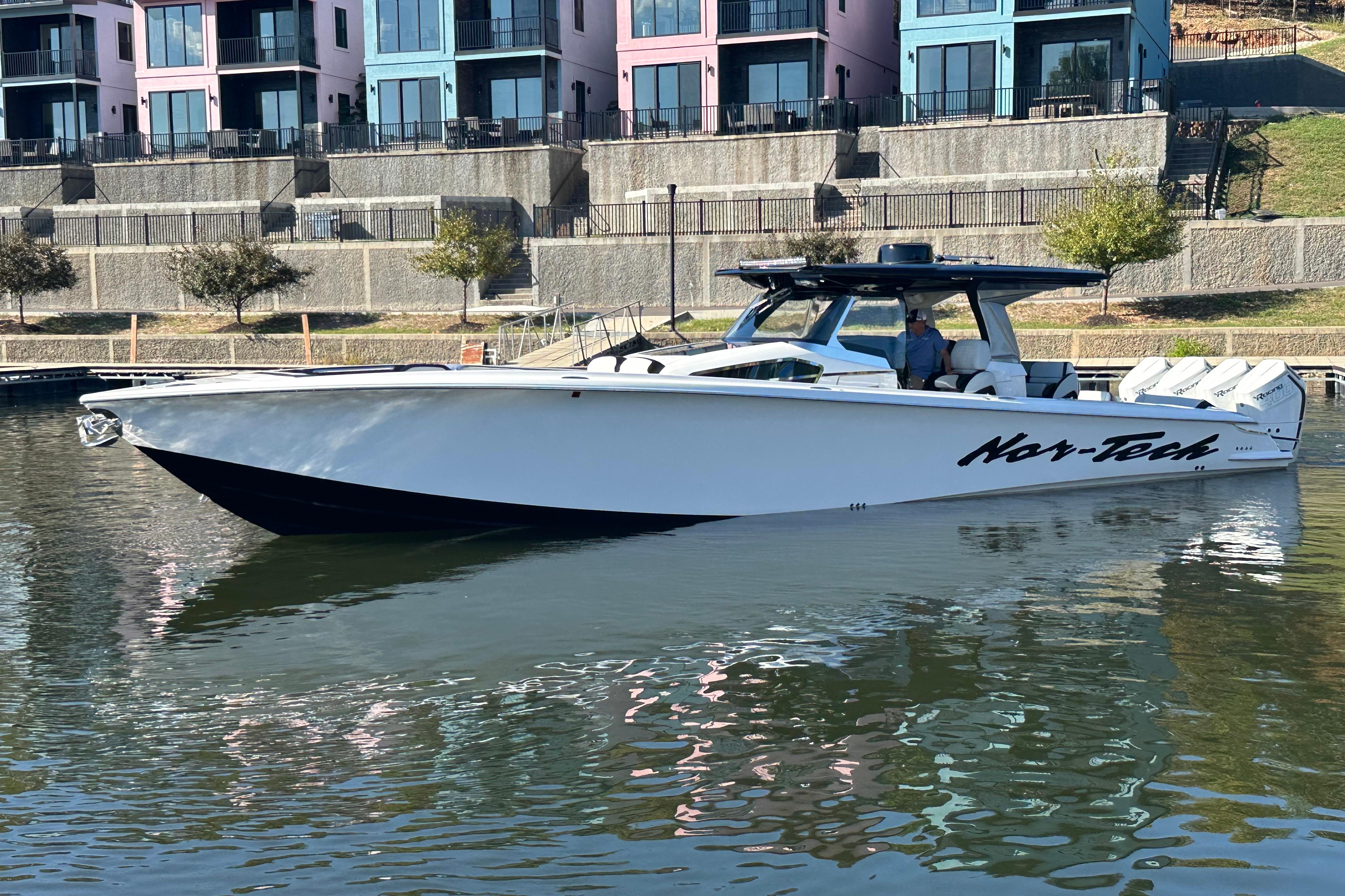 2025 Nor-Tech 450 Sport Center Console boat docked near colorful buildings.