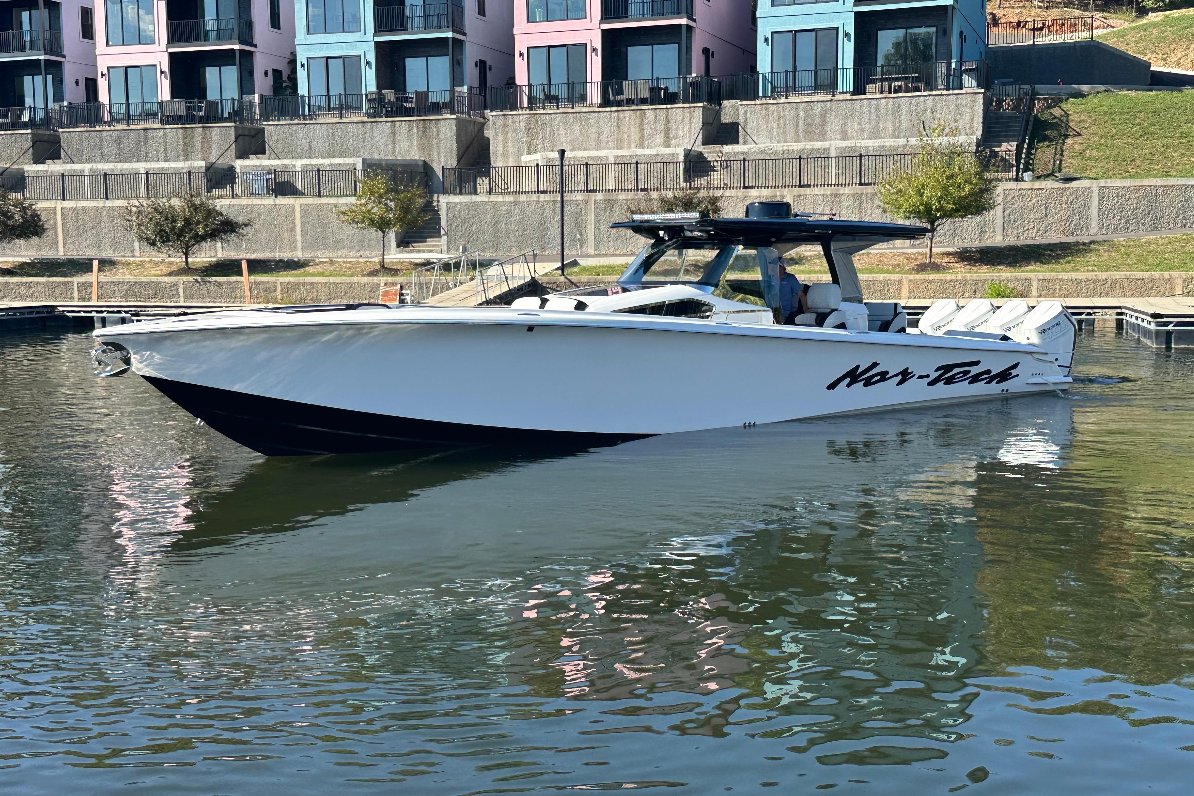 2025 Nor-Tech 450 Sport Center Console boat docked near colorful buildings.