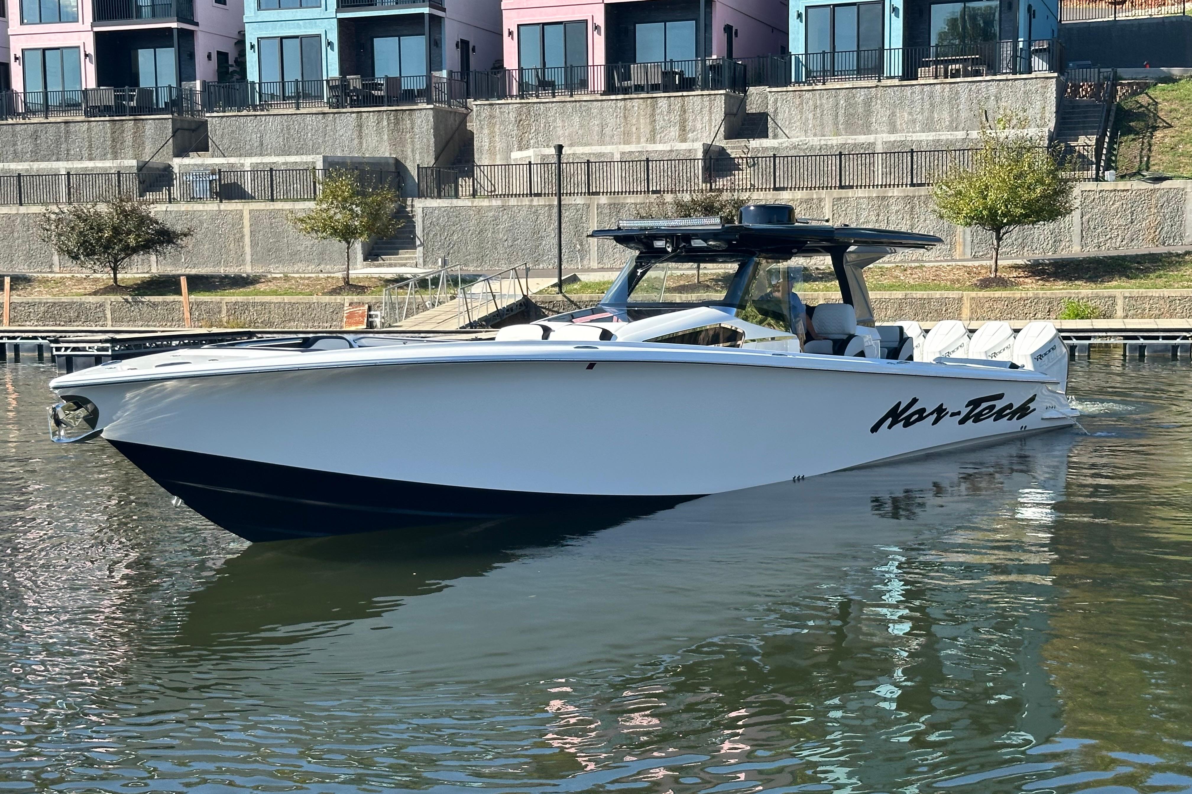 2025 Nor-Tech 450 Sport Center Console boat docked near colorful buildings.