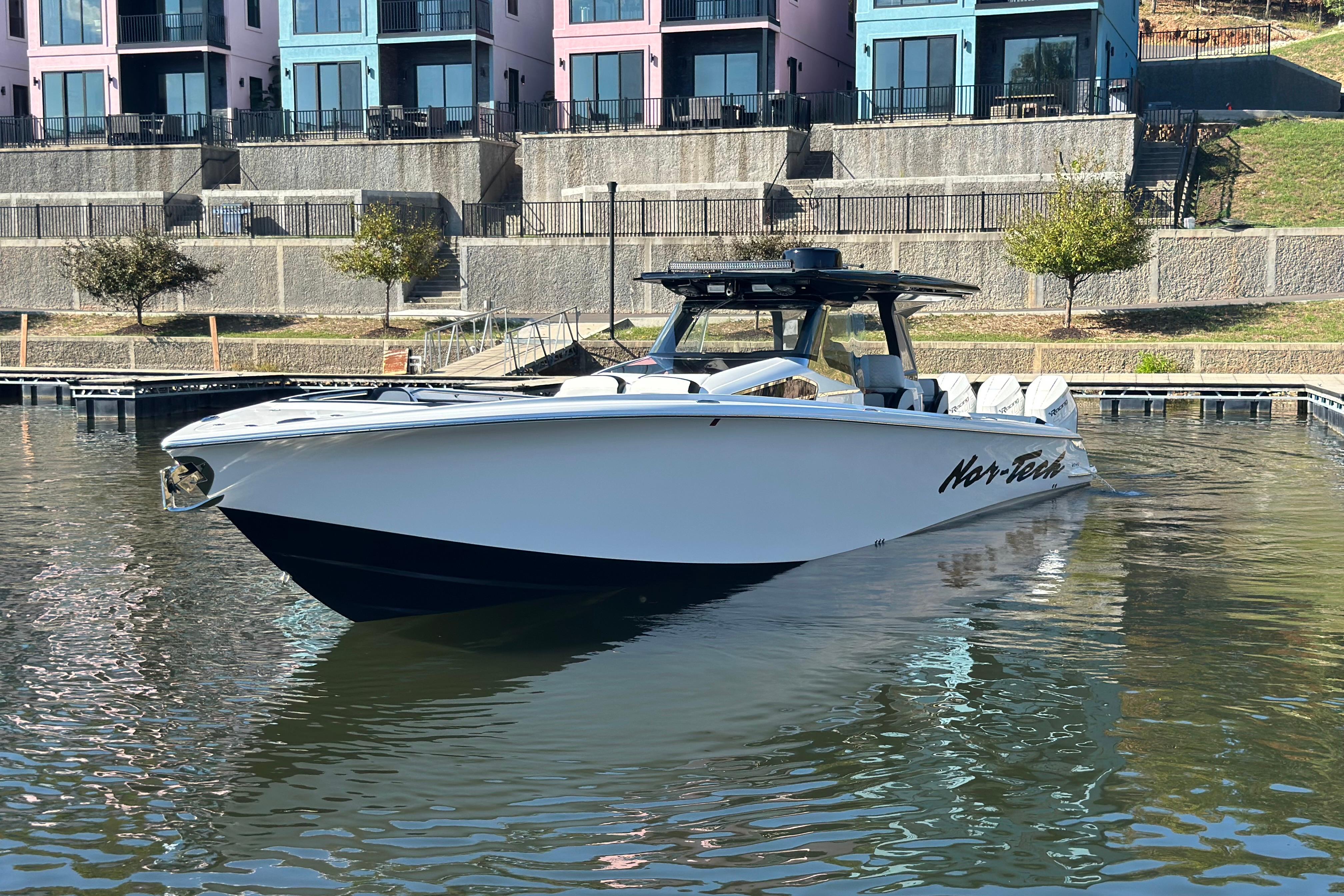 2025 Nor-Tech 450 Sport Center Console boat docked near colorful waterfront buildings.