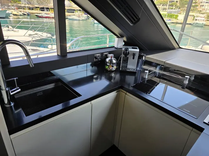 Orca Yacht Photos Pics Modern kitchen interior on 2023 Cranchi Sessantasette 67 yacht, featuring sleek black countertops.