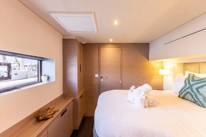 Port To Vino 2 Yacht Photos Pics Luxurious bedroom interior of 2023 Fountaine Pajot Samana 59 yacht with modern decor.