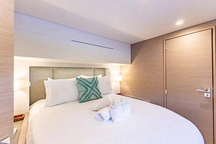 Port To Vino 2 Yacht Photos Pics Luxurious bedroom interior on 2023 Fountaine Pajot Samana 59 yacht, featuring elegant bedding and soft lighting.