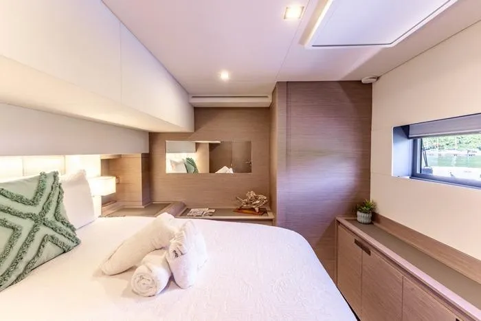 Port To Vino 2 Yacht Photos Pics Luxurious cabin interior of 2023 Fountaine Pajot Samana 59 yacht, featuring elegant design and cozy bedding.