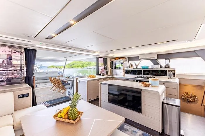 Port To Vino 2 Yacht Photos Pics Luxurious interior of 2023 Fountaine Pajot Samana 59 yacht with modern kitchen and dining area.