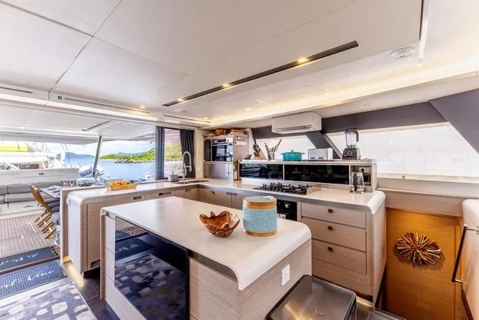 Port To Vino 2 Yacht Photos Pics Luxurious interior of 2023 Fountaine Pajot Samana 59 yacht kitchen and dining area.