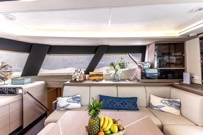 Port To Vino 2 Yacht Photos Pics Luxurious interior of 2023 Fountaine Pajot Samana 59 yacht with elegant decor and fruit display.