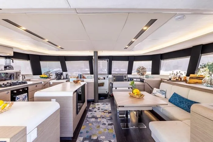 Port To Vino 2 Yacht Photos Pics Luxurious interior of 2023 Fountaine Pajot Samana 59 yacht with modern kitchen and seating area.