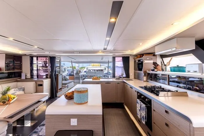 Port To Vino 2 Yacht Photos Pics Luxurious interior of 2023 Fountaine Pajot Samana 59 yacht with modern kitchen and seating area.
