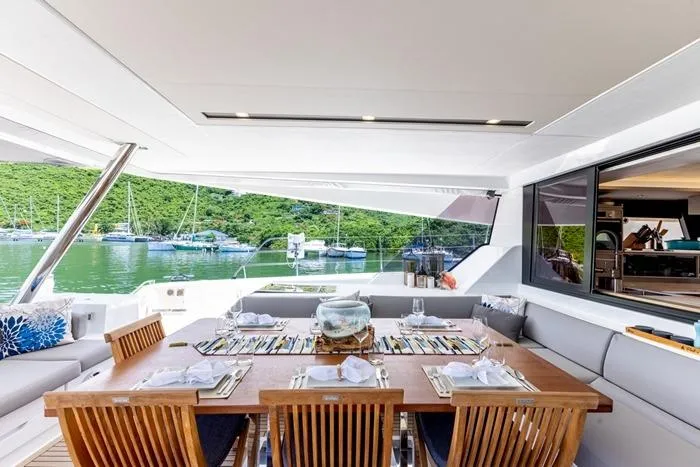 Port To Vino 2 Yacht Photos Pics Luxurious dining area on 2023 Fountaine Pajot Samana 59 yacht, overlooking serene waters and lush greenery.