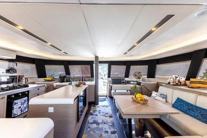 Port To Vino 2 Yacht Photos Pics Luxurious interior of 2023 Fountaine Pajot Samana 59 yacht with modern kitchen and seating area.