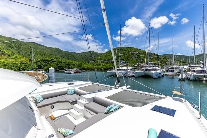 Port To Vino 2 Yacht Photos Pics 2023 Fountaine Pajot Samana 59 catamaran docked in a scenic marina with lush hills.