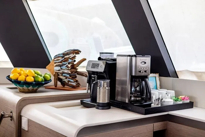 Port To Vino 2 Yacht Photos Pics Modern kitchen area on 2023 Fountaine Pajot Samana 59 yacht with coffee makers and fruit bowl.