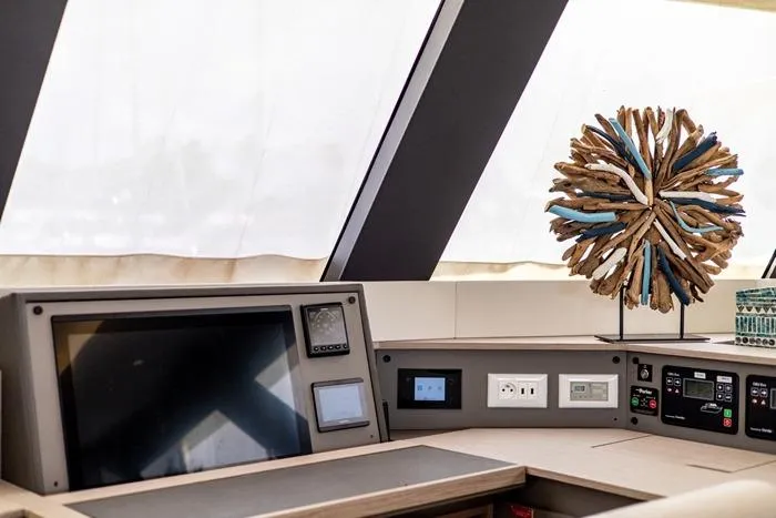 Port To Vino 2 Yacht Photos Pics 2023 Fountaine Pajot Samana 59 yacht interior with navigation equipment and decorative sculpture.