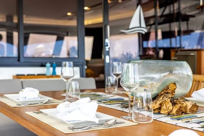 Port To Vino 2 Yacht Photos Pics Elegant dining setup on 2023 Fountaine Pajot Samana 59 yacht, featuring glassware and nautical decor.