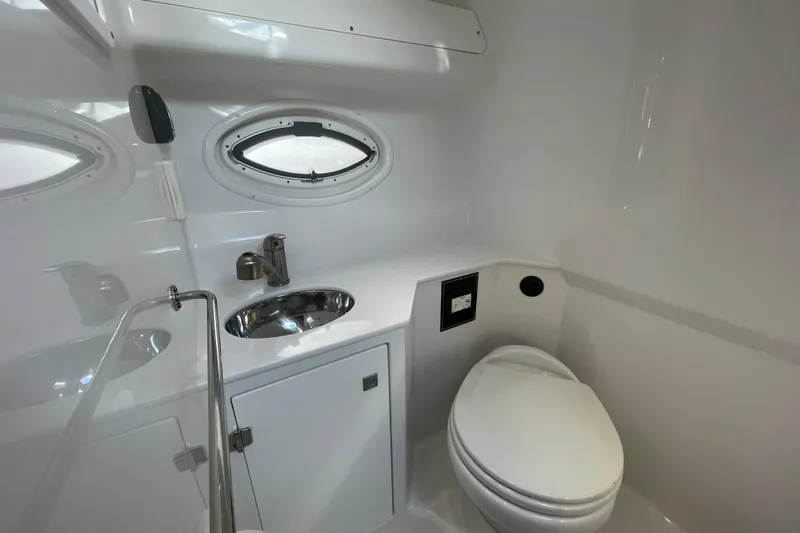  Yacht Photos Pics 2019 Monterey 295 Sport Yacht bathroom with sink, toilet, and oval window.