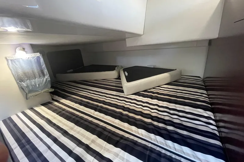  Yacht Photos Pics 2019 Monterey 295 Sport Yacht interior cabin with striped bedding and storage compartments.