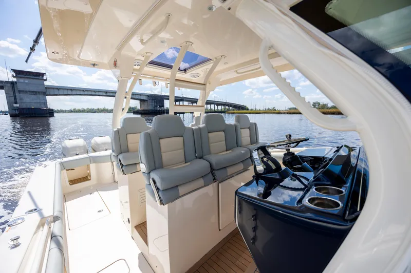  Yacht Photos Pics 2019 Scout 420 LXF boat interior with luxurious seating and helm, near a bridge on a sunny day.