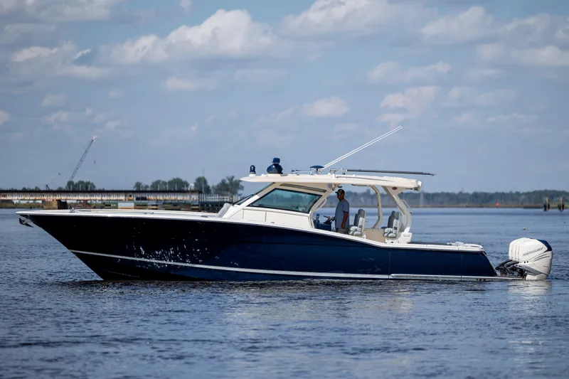  Yacht Photos Pics 2019 Scout 420 LXF boat cruising on a calm waterway under a blue sky.