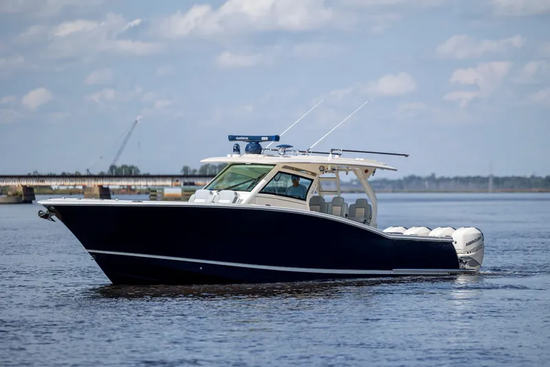  Yacht Photos Pics 2019 Scout 420 LXF boat cruising on a calm waterway under a partly cloudy sky.