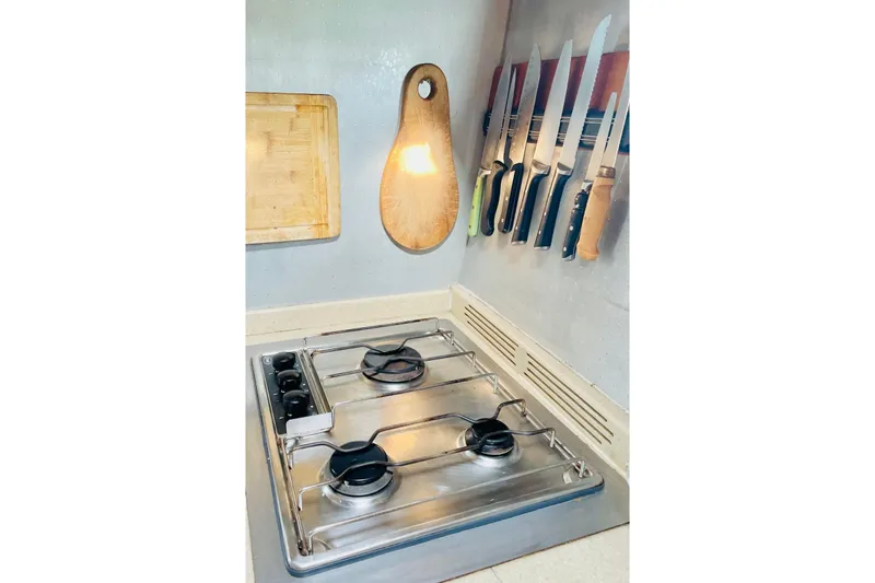 Macera Yacht Photos Pics Compact kitchen setup in Privilege 495 yacht, featuring stove, cutting board, and knife rack.