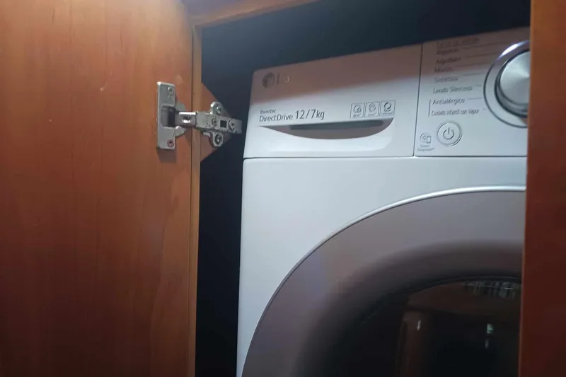 Macera Yacht Photos Pics Washing machine inside wooden cabinet, partially visible, with door hinge exposed.