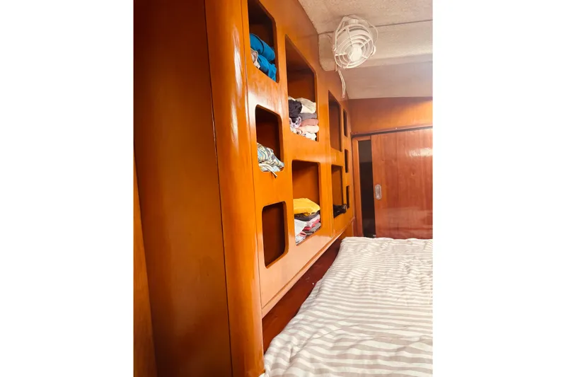 Macera Yacht Photos Pics Interior of 2008 Privilege 495 yacht with wooden shelves and striped bedding.