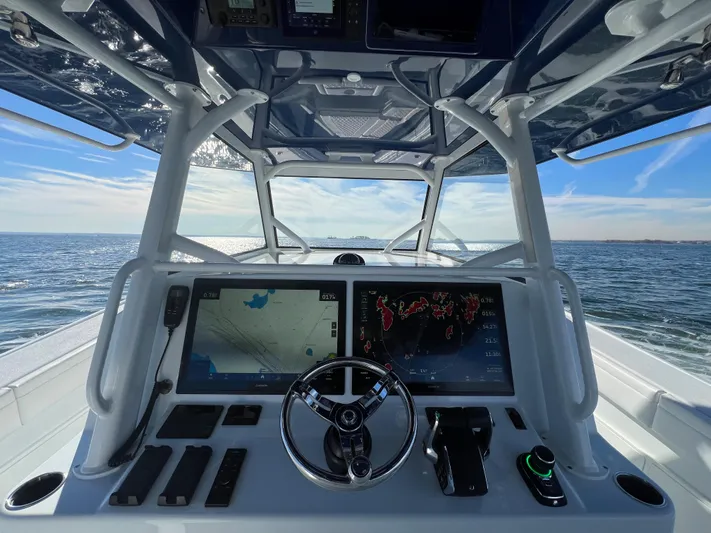  Yacht Photos Pics 2023 Yellowfin 42 Offshore boat dashboard with navigation screens, steering wheel, and ocean view.