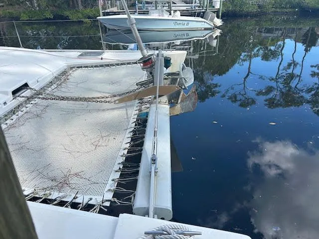  Yacht Photos Pics 1995 Lagoon TPI 37 catamaran docked on calm water with reflections of trees.