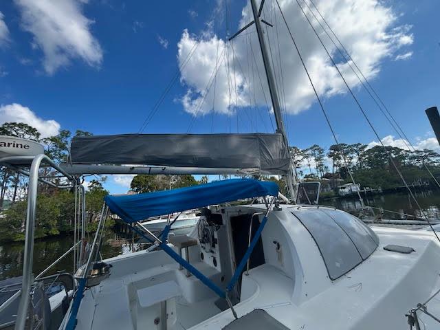 1995 Lagoon TPI 37 sailboat with blue canopy, docked under a clear sky.