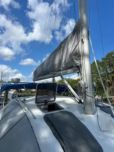  Yacht Photos Pics 1995 Lagoon TPI 37 sailboat with gray sail, under blue sky and clouds.