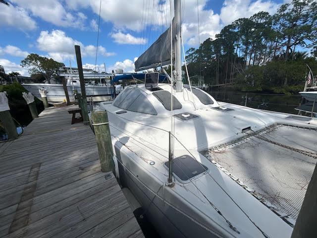 1995 Lagoon TPI 37 catamaran docked, featuring sleek design and spacious deck under a blue sky.