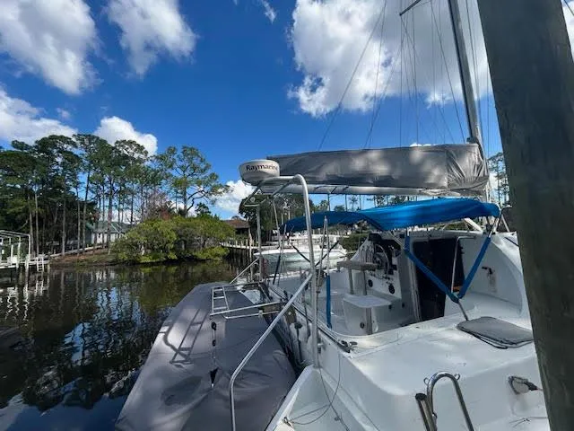  Yacht Photos Pics 1995 Lagoon TPI 37 sailboat docked on a serene waterway under a clear blue sky.