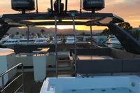 Luxurious Astondoa A76 GLX yacht deck at sunset, featuring a jacuzzi and marina view.