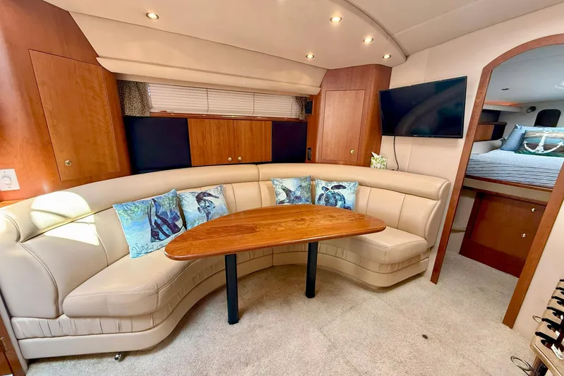 Creme Brulee Yacht Photos Pics Luxurious 2001 Cruisers Yachts 4270 Express interior with curved seating, wooden table, and TV.