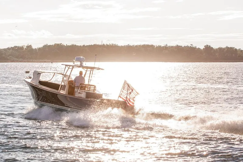 Wayfarer Yacht Photos Pics Hinckley Talaria 29C boat cruising on sunlit water, 2002 model, with American flag.