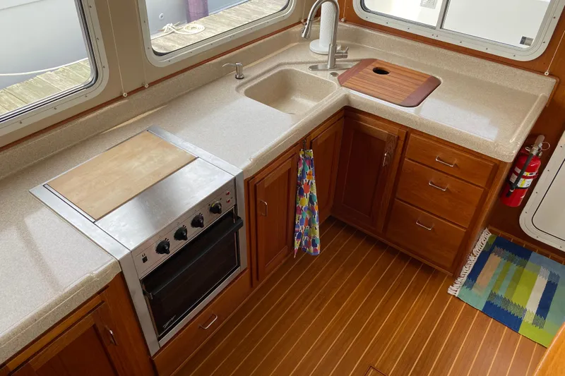 Emilie B Yacht Photos Pics Interior view of 2003 American Tug 34 kitchen with stove, sink, and wooden cabinetry.