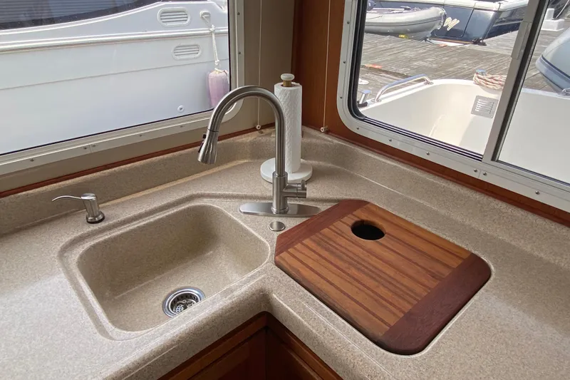 Emilie B Yacht Photos Pics Kitchen sink area in a 2003 American Tug 34, featuring a cutting board and faucet.