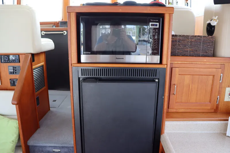 Emilie B Yacht Photos Pics Interior of 2003 American Tug 34 featuring microwave and refrigerator in wooden cabinetry.