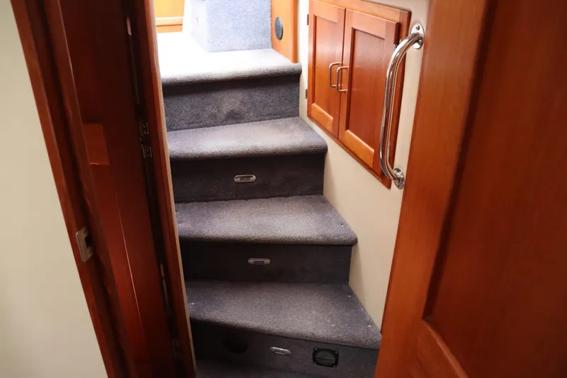 Emilie B Yacht Photos Pics Carpeted stairs inside a 2003 American Tug 34 boat, featuring wooden cabinetry and a metal handrail.