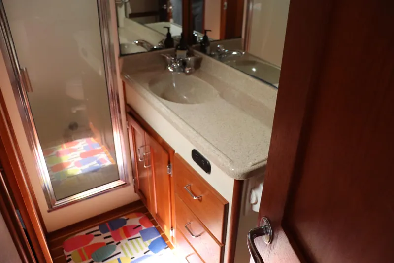 Emilie B Yacht Photos Pics Bathroom interior of 2003 American Tug 34 with colorful rug and wooden cabinetry.