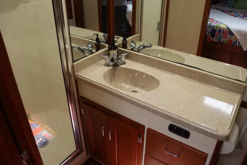 Emilie B Yacht Photos Pics Bathroom vanity in 2003 American Tug 34 with sink, mirror, and wooden cabinetry.