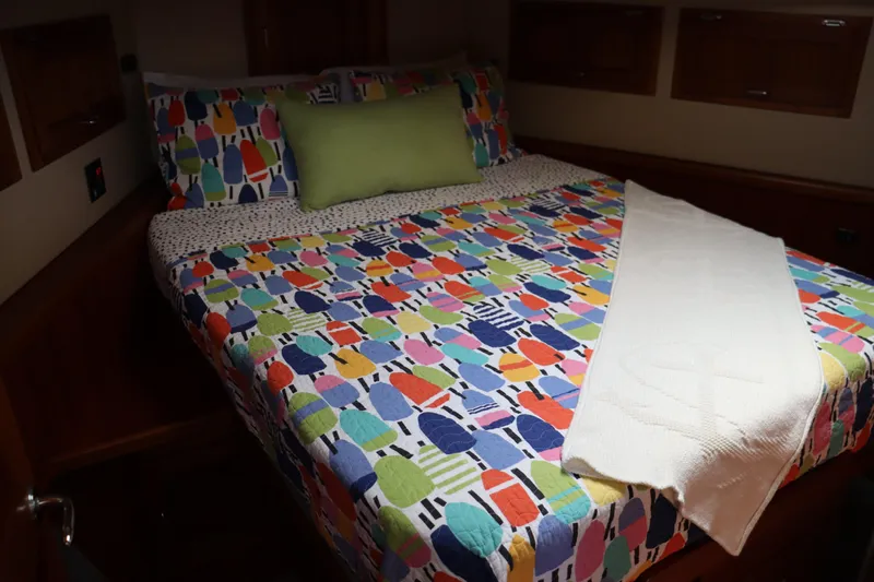 Emilie B Yacht Photos Pics Cozy cabin bedroom in 2003 American Tug 34 with colorful bedding and wooden accents.