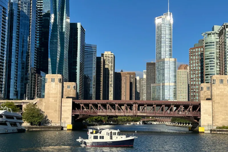 Emilie B Yacht Photos Pics A 2003 American Tug 34 boat on a river with a city skyline backdrop.