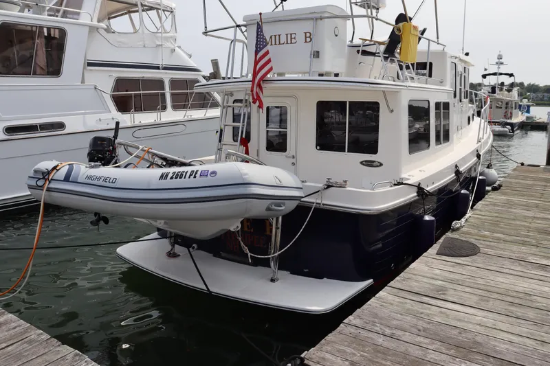 Emilie B Yacht Photos Pics American Tug 34, 2003 model, docked with a small dinghy attached at the stern.