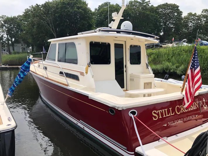  Yacht Photos Pics 2009 Sabre 40 Sedan boat docked, red hull, American flag, lush greenery in background.